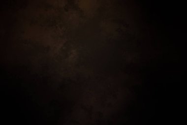 Siyah bir arka planın önünde duran takım elbiseli ve kravatlı bir adam.