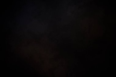 Siyah bir arka planın önünde duran takım elbiseli ve kravatlı bir adam.