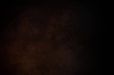 Takım elbiseli ve kravatlı bir adam karanlık bir arka planın önünde duruyor.