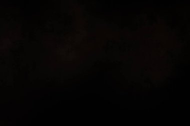 Siyah bir arka planın önünde duran takım elbiseli ve kravatlı bir adam.