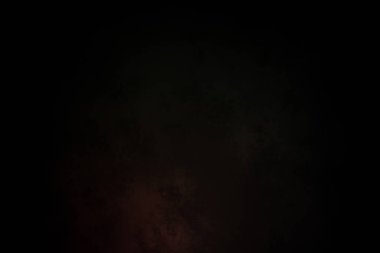 Siyah bir arka planın önünde duran takım elbiseli ve kravatlı bir adam.