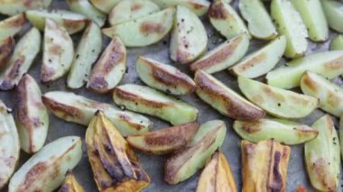 Patates dilimleri fırın tepsisindeki sıcak fırında pişirilir. Kızarmış köy patatesleri..