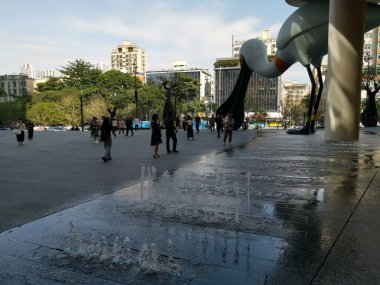 China, Shenzhen - October 25, 2024 : A large bird sculpture overlooks a fountain in a public square, with people walking by. clipart