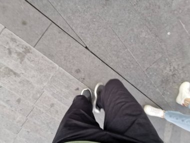 Çin, Shenzhen - 25 Ekim 2024: Büyük bir alışveriş merkezinin önündeki kaldırımda yürüyen bir insanın bacaklarının birinci şahıs perspektifi.