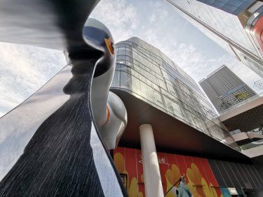 Çin, Shenzhen - 25 Ekim 2024: Shenzhen, Çin 'deki modern bir alışveriş merkezinin ön planda büyük bir soyut heykeli ile düşük açılı çekimi.