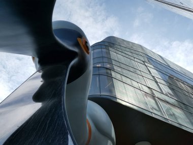 Çin, Shenzhen - 25 Ekim 2024: Çin 'de modern, cam bir binanın önünde geniş, beyaz, soyut bir heykelin düşük açılı görüntüsü.