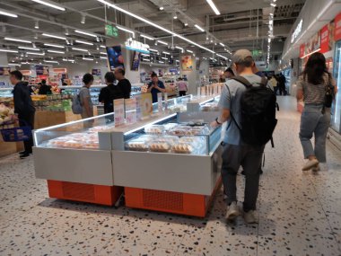 Çin, Shenzhen - 25 Ekim 2024: Çin 'de modern bir alışveriş merkezi, çeşitli hamur işlerine bakan müşterilerin bulunduğu bir pastane bölümü sergileniyor.