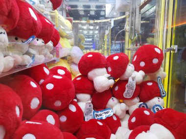 Çin, Shenzhen - 25 Ekim 2024: Bir alışveriş merkezinde kırmızı ve beyaz mantar peluş oyuncaklarla dolu bir pençe makinesi.