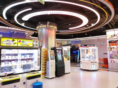 Çin, Shenzhen - 25 Ekim 2024: Bir alışveriş merkezindeki parlak ışıklı bir atari salonunda pençe makineleri, yarış oyunları ve ödül kurtuluş oyunları gibi çeşitli atari oyunları yer alıyor..