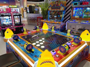 Çin, Shenzhen - 25 Ekim 2024: Shenzhen, Çin 'deki parlak ışıklı bir alışveriş merkezinde atari oyunu. Oyunda birkaç renkli düğmesi olan bir dijital ekran yer alıyor.