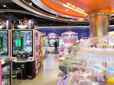 Çin, Shenzhen - 25 Ekim 2024: Bir alışveriş merkezinde çeşitli video oyunları ve pençe makineleri olan parlak ışıklı bir oyun salonu.