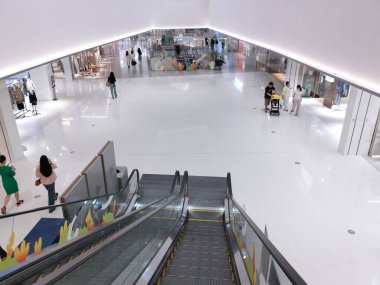 Çin, Shenzhen - 25 Ekim 2024: Beyaz fayanslı döşemeleri, yürüyen merdivenleri ve birkaç müşterisi olan geniş bir alışveriş merkezi.