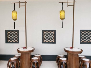 Çin, Shenzhen - 25 Ekim 2024: Ahşap çerçeveli pencereler ve geleneksel Çin fenerleriyle beyaz bir duvarın önünde iki yuvarlak masa.