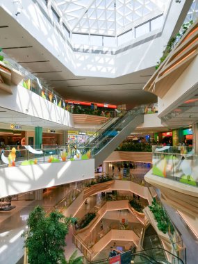 Çin, Shenzhen - 25 Ekim 2024: Shenzhen, Çin 'de geometrik cam tavanı, yürüyen merdivenleri ve yeşillikleri olan modern bir alışveriş merkezi.