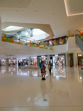 Çin, Shenzhen - 25 Ekim 2024: Shenzhen, Çin 'de beyaz fayanslı zemini, yürüyen merdivenleri ve alışveriş yapan insanları olan modern bir alışveriş merkezinin içi.