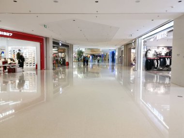 Çin, Shenzhen - 25 Ekim 2024: Shenzhen, Çin 'de modern bir alışveriş merkezi. Parlak beyaz zemin ve tavan havadar bir atmosfer yaratır..