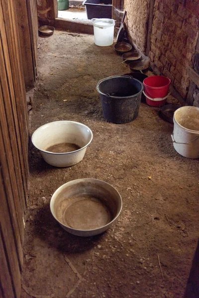 In an attic with a leaking roof, there are bowls and buckets to catch the rainwater. in summer.
