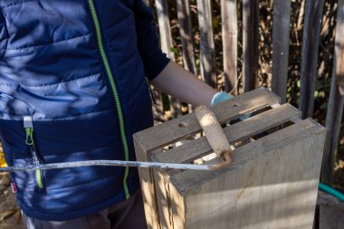 Bir çocuk, bahçesinde fırça olan ahşap bir kutu boyuyor.