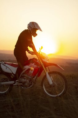 young man riding motorcycle on sunset background