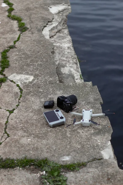 Siyah bir arka planı olan beyaz bir dron yerde yatıyor.
