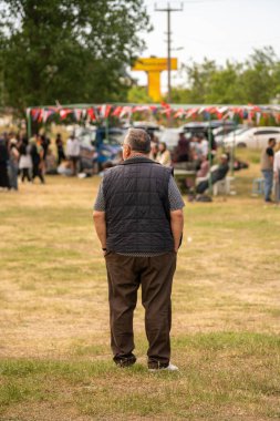 Yeşil gömlekli bir adam sokakta dikiliyor.