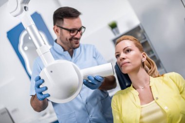 Diş hekimi, diş sağlığı kliniğindeki hastaya diş röntgeni çektirmeye hazırlanıyor. İnsanlar, ilaç, stomatoloji ve sağlık konsepti.