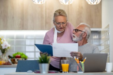 Evde kıdemli bir çift, faturaları internetten ödemeye hazırlanıyor. Çevrimiçi ödeme.