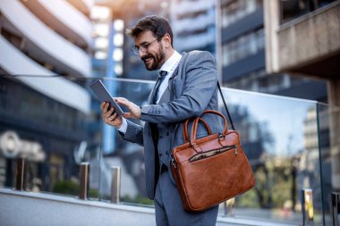 İşadamı ofisinin önünde dijital tablet kullanıyor, video görüşmesi yapıyor..