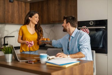 Genç adam dizüstü bilgisayarla uğraşırken mutfakta oturuyor. Evde dizüstü bilgisayarla çalışan genç bir serbest yazar..