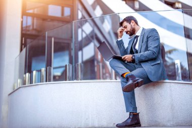 Portrait of a upset businessman looking at laptop outdoors,he having hard day on work.