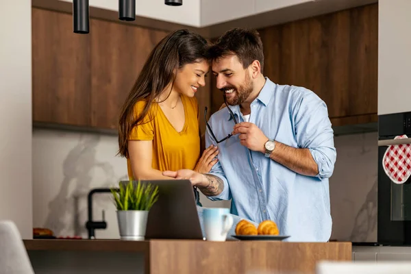 Stock image Couple using laptop while drink coffee in their kitchen.Couple in modern kitchen using laptop.