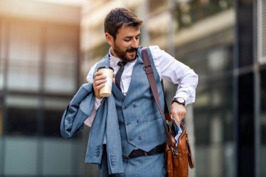 Başarılı bir iş adamı, bir iş toplantısına gidiyor, arkasında modern ofis binası var..