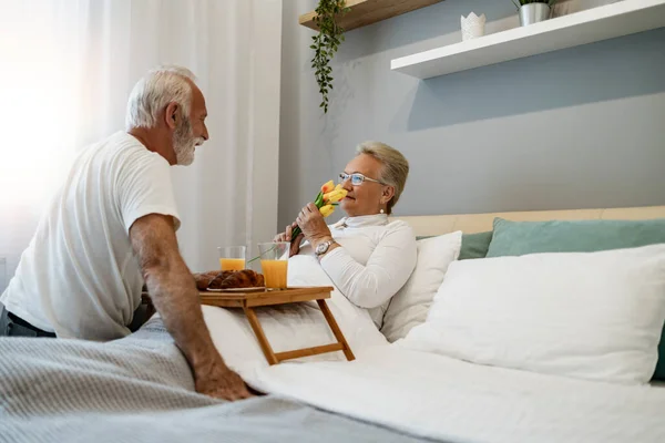 stock image Breakfast in bed. Senior man bringing breakfast to his wife in bedroom.