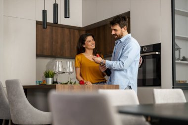 Bir çift modern mutfaklarında romantik bir anı paylaşıyor, gülümsüyor ve birlikte kaliteli zaman geçiriyorlar. Çağdaş ayar onların etkileşimlerine sıcaklık ve samimiyet ekler..