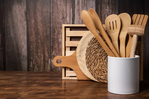 木制厨房用具 排水管和其他厨房用具 在切板和三叶草旁边的一个罐子里 旁边有一个粗糙的木制背景 — 图库照片