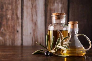 Ekstra saf zeytinyağlı yağ tenekeleri kırsal ahşap arka planda, zeytinli yaprakların yanında.. 