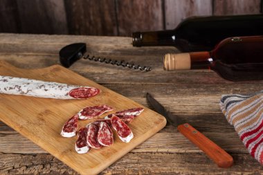 İspanya 'nın dört bir yanına yayılmış domuz eti ve domuz pastırması üzerine kurulu, ahşap bir kesme tahtasıyla dilimlenmiş, tipik Katalan sosisi ve birkaç şişe şarap..