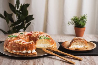 Roscon de Reyes. Tahta bir tabakta bir parça kesilmiş. İçindeki kremayı ortaya çıkarıyor. Yakın plan..