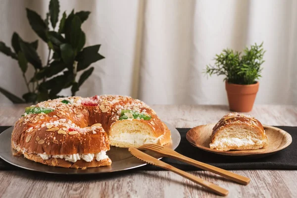 Roscon de Reyes. Tahta bir tabakta bir parça kesilmiş. İçindeki kremayı ortaya çıkarıyor. Yakın plan..