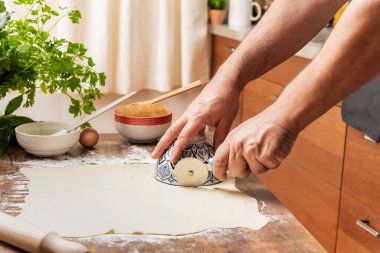 Cook's hands cutting a puff pastry dough to make sweets filled with angel hair.