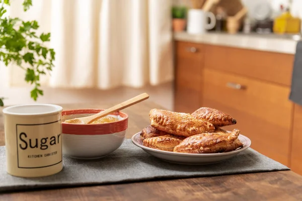 Puff pastry sweets stuffed with angel hair on the kitchen table of a home, next to the pumpkin and sugar candy, close-up.