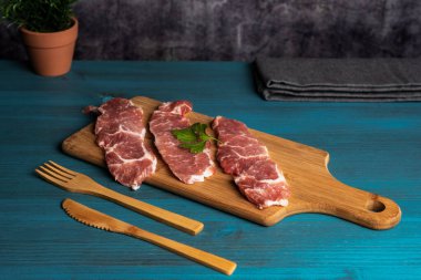 Iberian pork loin steaks on a cutting board, on a rustic wooden table.