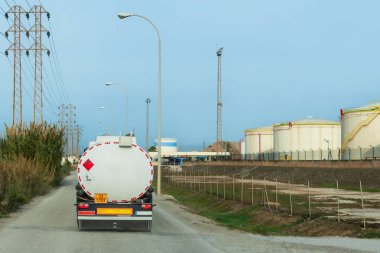 Yakıt taşımak için bir tanker, yakıt depolama tanklarıyla dolu bir yükleme tesisine varıyor..