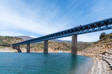 Granada 'daki baraj gölünün üzerinde beton temelleri olan metal köprü. .