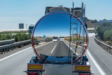 Ayna efektli bir tankerin arkasında bir kamyon ve bir otobüs yansıtılır..