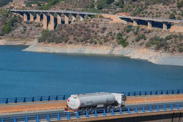 Tanker truck for the transport of fuels circulating on a bridge, in the background several more viaducts.Landscape.