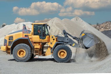 Tekerlek yükleyiciler bir taş ocağında kum taşıyorlar. Yakın plan..