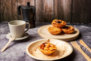 Pasteis de nata, Lizbon, Portekiz 'den tipik bir tatlı, tabakta bir fincan kahvenin yanında bir pasta..