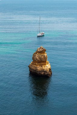 Punta de la Piedad 'da arka planda yelkenlisi olan bir ada, Faro, Algarve..