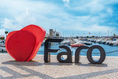 Faro 'nun adı büyük bir kalbin yanında, turist fotoğrafları için tipik bir yer, marinası arkada, Algarve..
